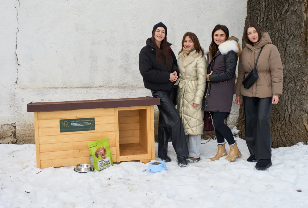 Жінки біля дерев'яного будиночка для собак взимку