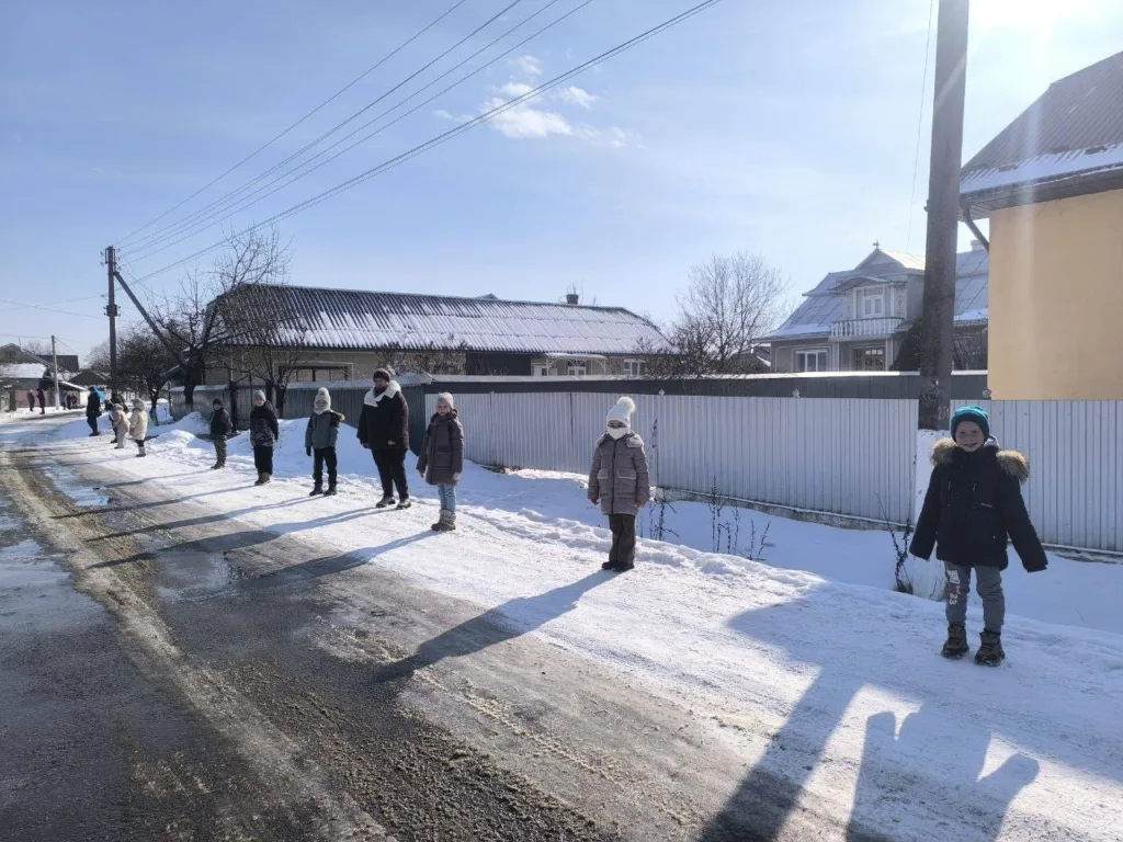 Діти стоять вздовж сніжної вулиці взимку