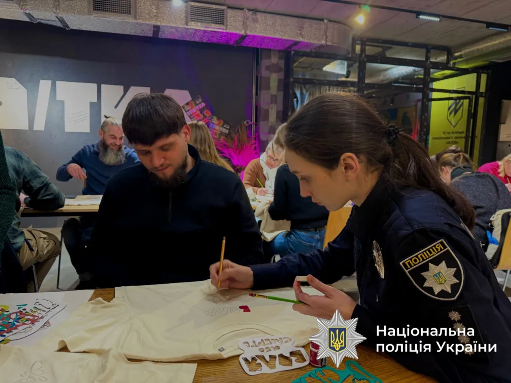 Поліцейська допомагає чоловікові малювати на майстер-класі