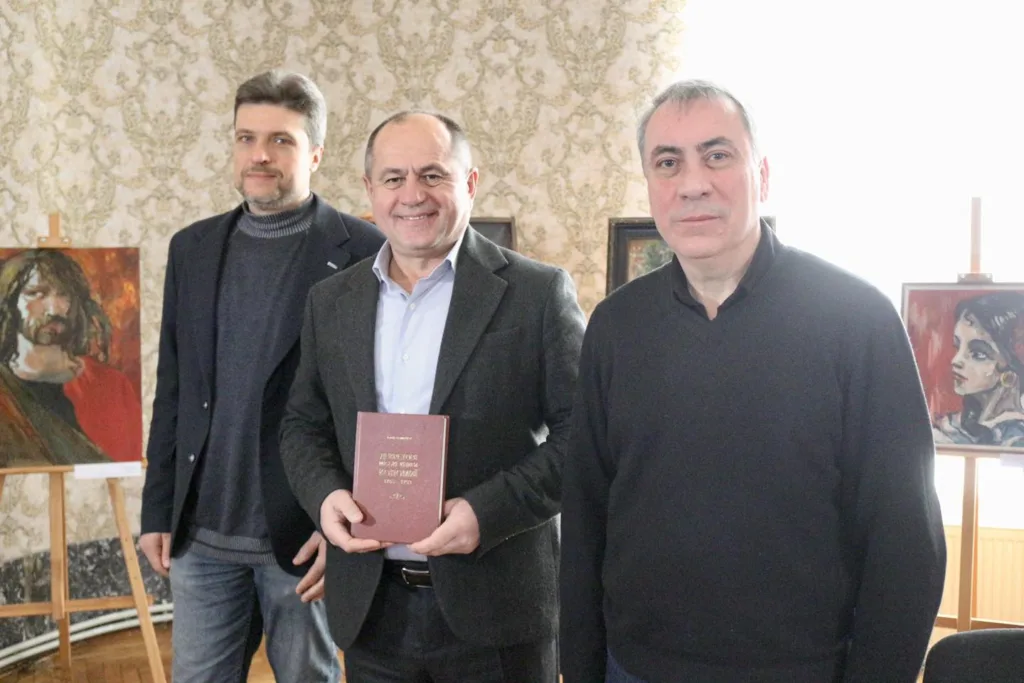 Троє чоловіків на виставці з картинами