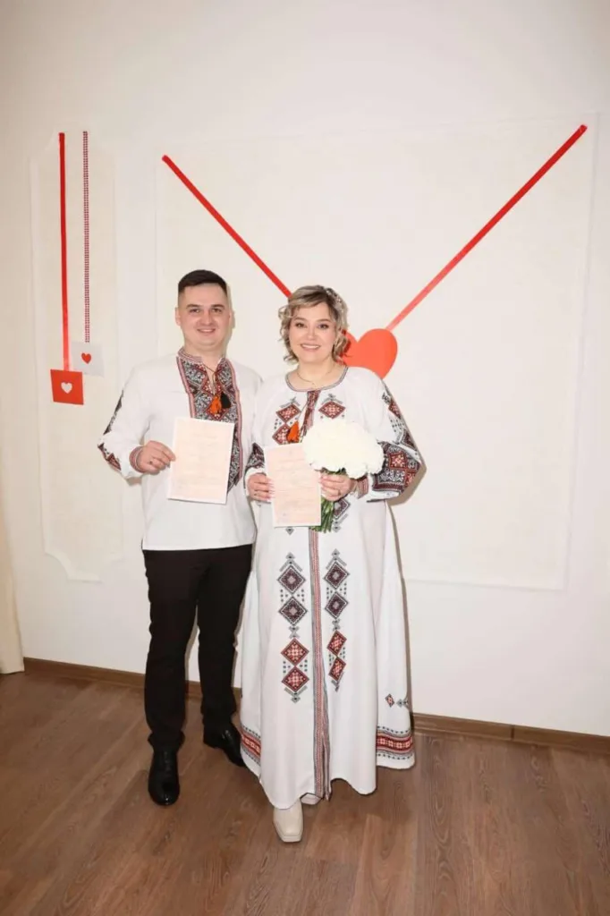 Молода пара у вишиванках тримає свідоцтва про шлюб