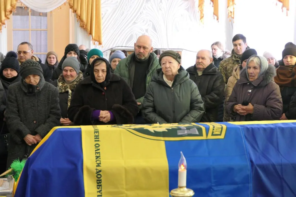 Люди прощаються із загиблим воїном під прапором України