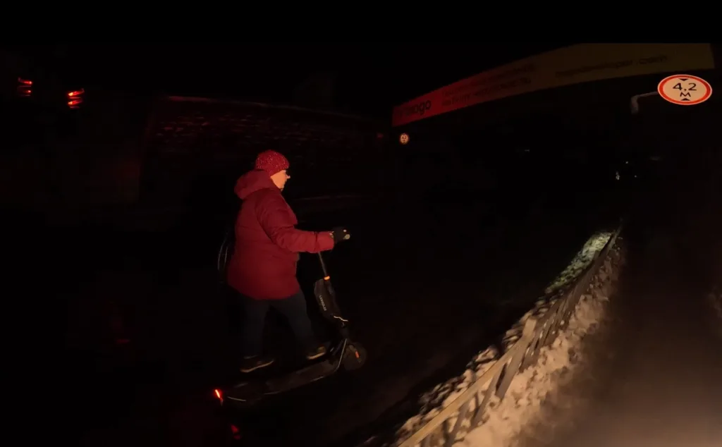 Людина на електросамокаті їде вночі взимку