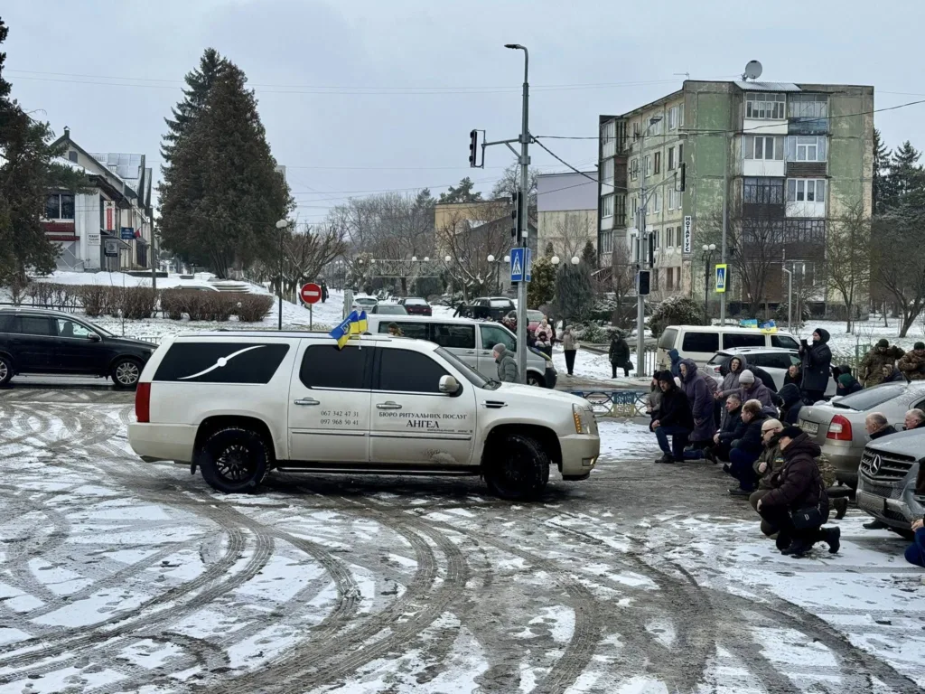 Люди на колінах прощаються з кортежем у місті