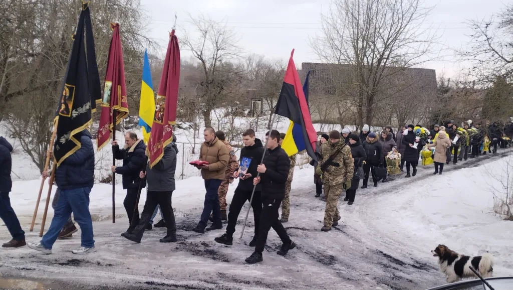 Похоронна процесія з прапорами на снігу в Україні