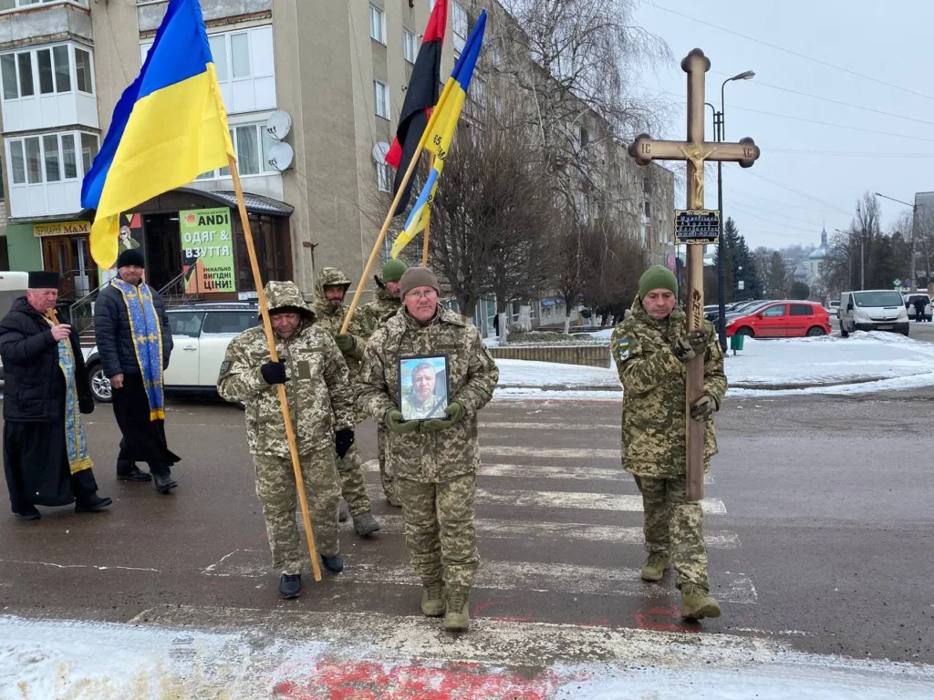 Військові несуть прапори та хрест на церемонії