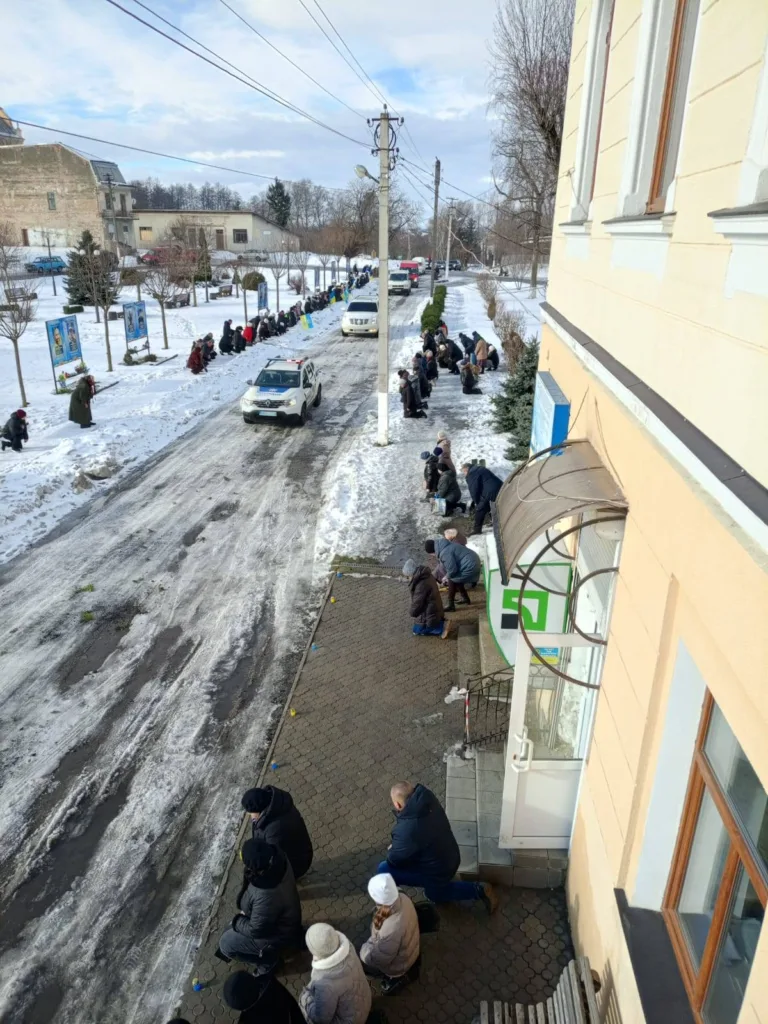 Люди стоять на колінах уздовж зимової дороги
