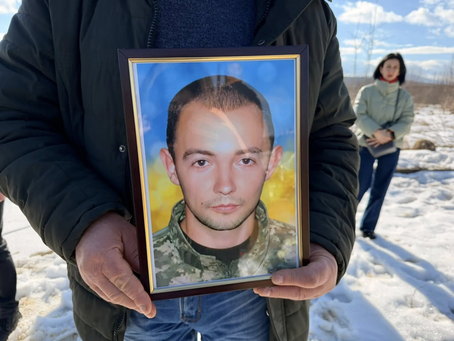 Людина тримає фото військового на тлі снігу