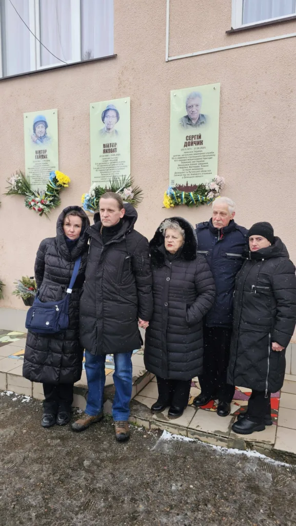 Люди вшановують пам'ять біля меморіальної стіни