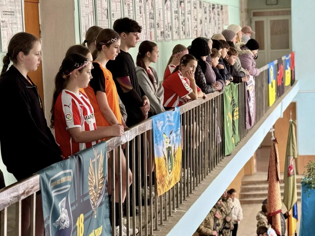 Люди стоять на балконі шкільного коридору