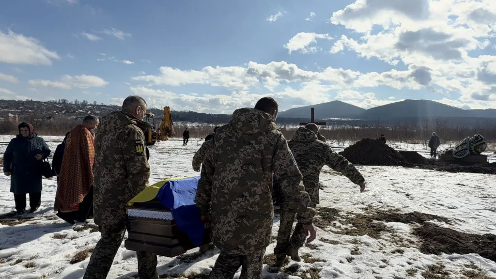 Військові несуть труну, накриту українським прапором