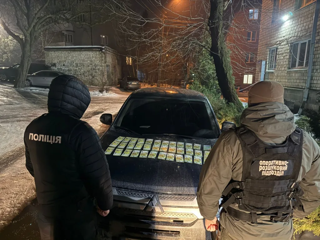 Поліція оглядає автомобіль із грошима на капоті