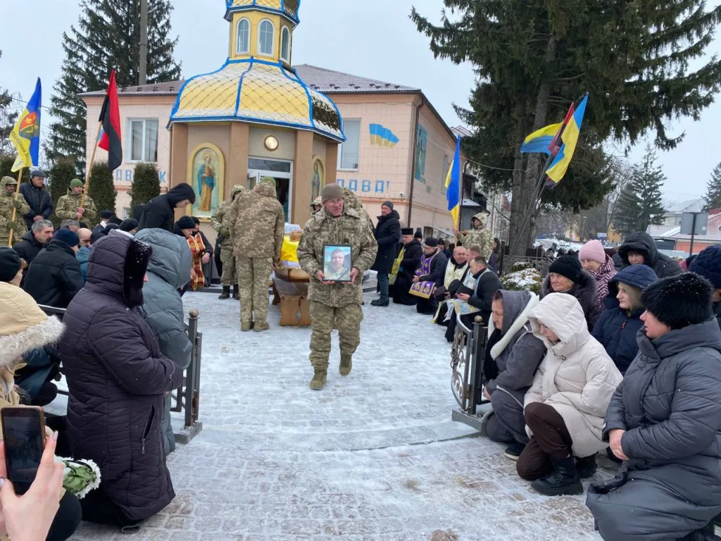 Похорон військового біля церкви з українськими прапорами