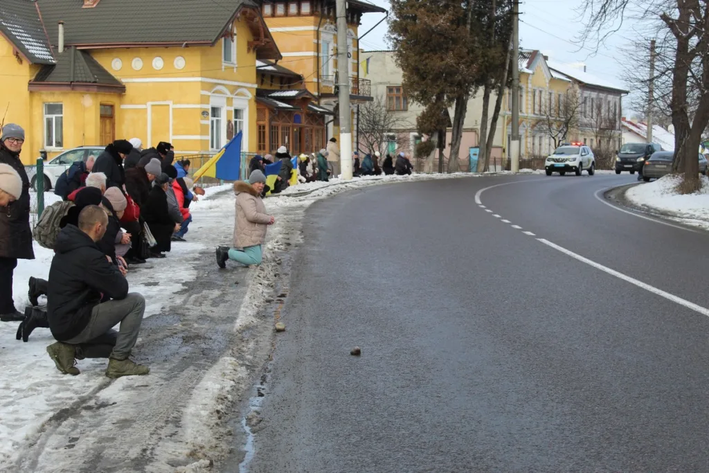 Люди стоять на колінах уздовж зимової дороги