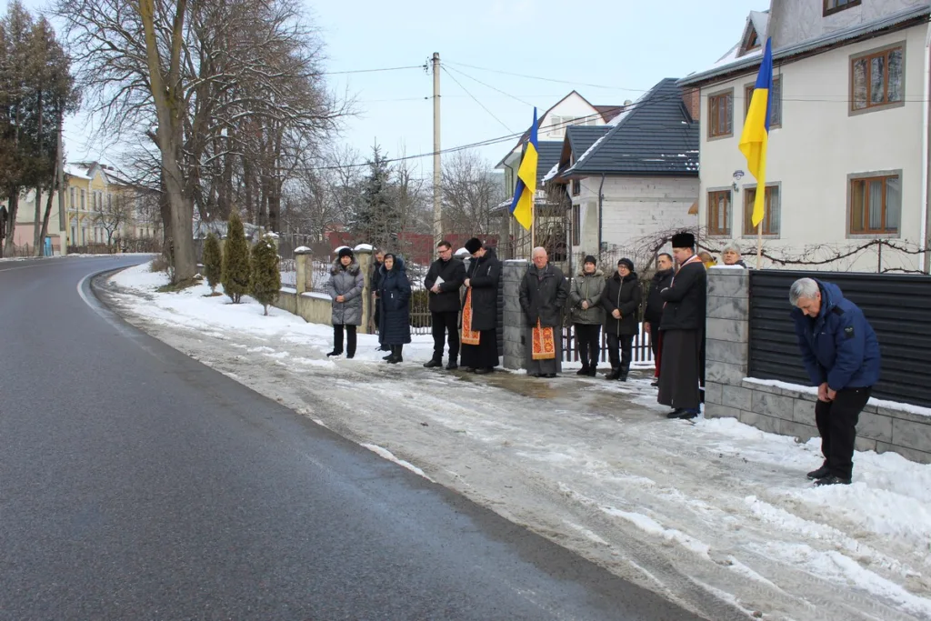 Люди стоять біля дороги з українськими прапорами