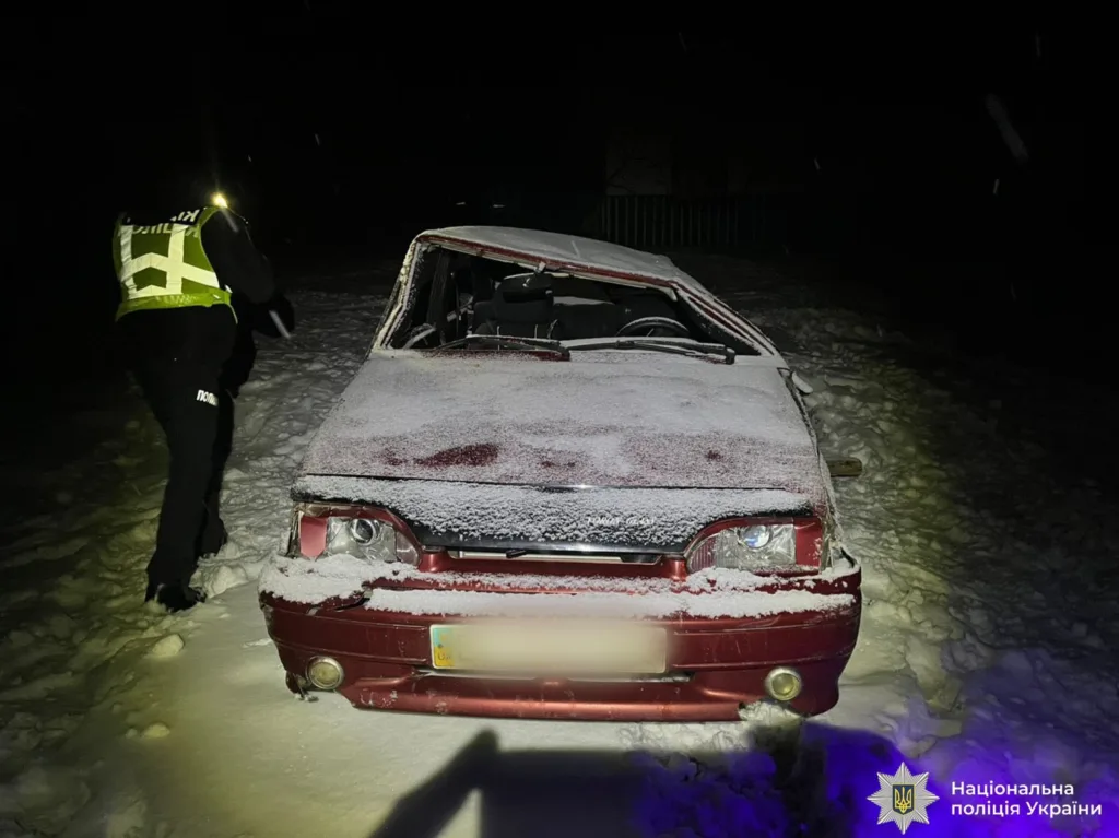 Поліція оглядає пошкоджений автомобіль у снігу вночі