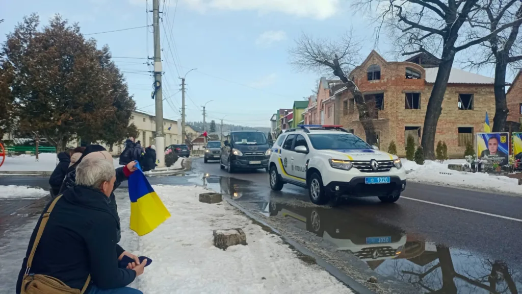 Поліцейський ескорт на зимовій вулиці з прапором України