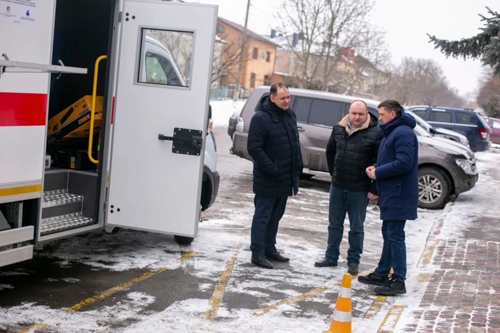 Троє чоловіків біля машини швидкої допомоги взимку