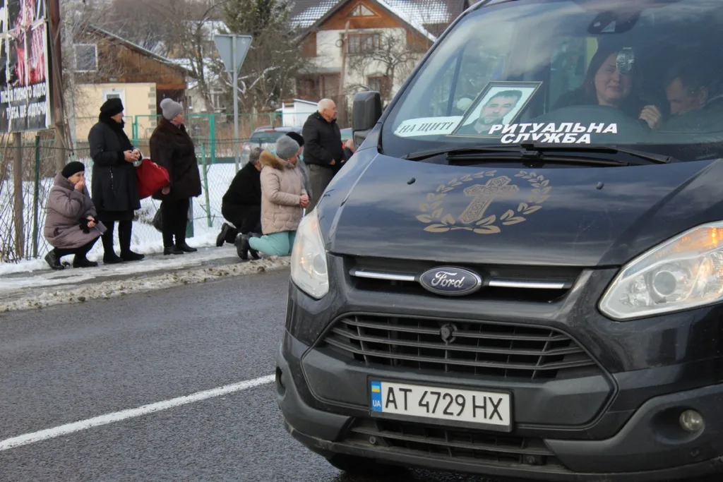 Люди прощаються з похоронним кортежем на вулиці