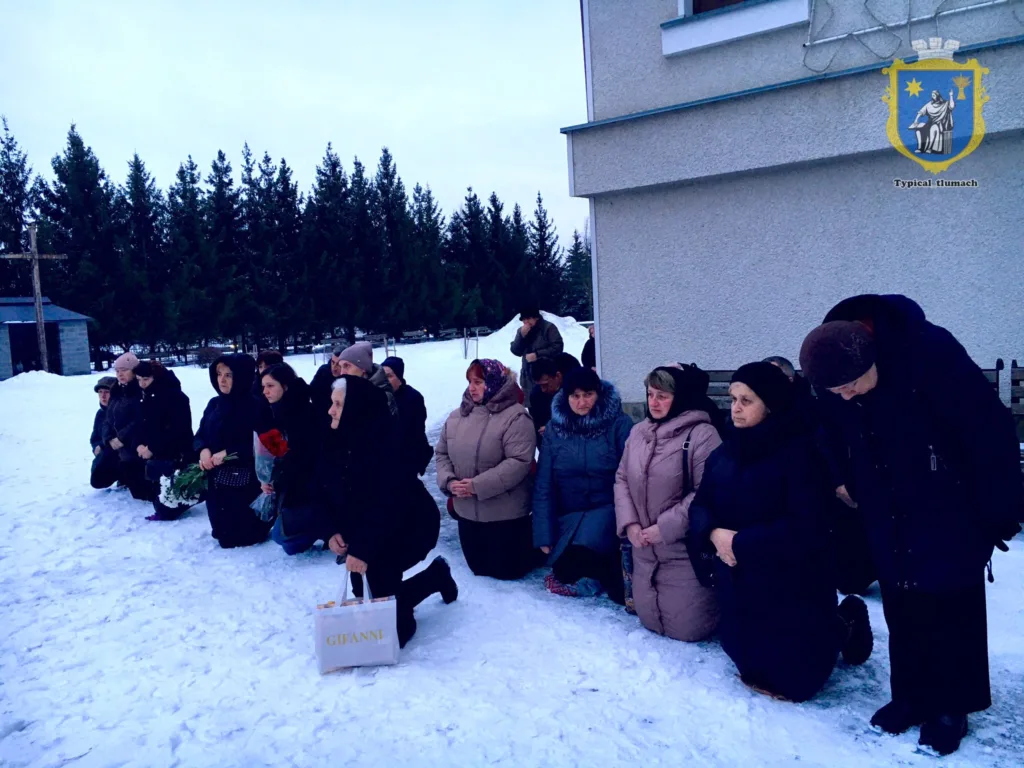 Люди моляться на колінах на снігу біля будівлі