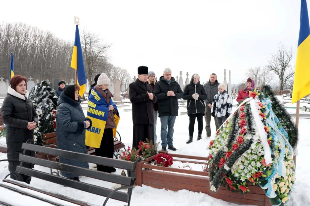 Люди вшановують пам’ять героя на цвинтарі взимку
