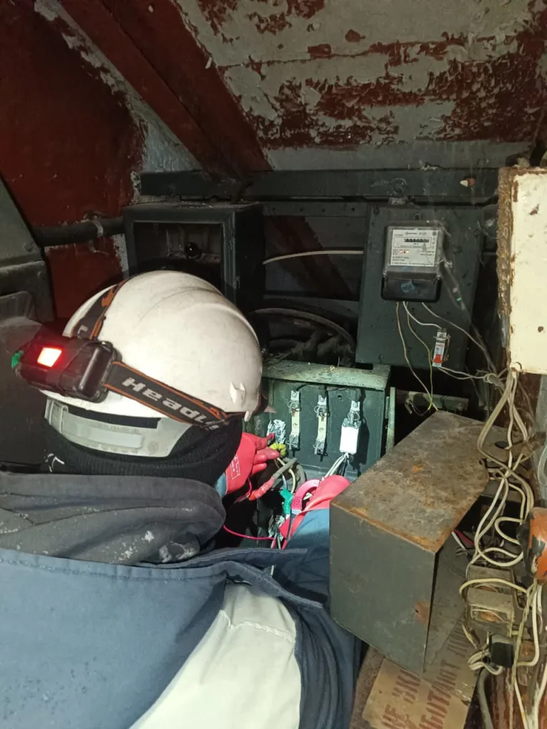 Електрик ремонтує електрощит у підвалі