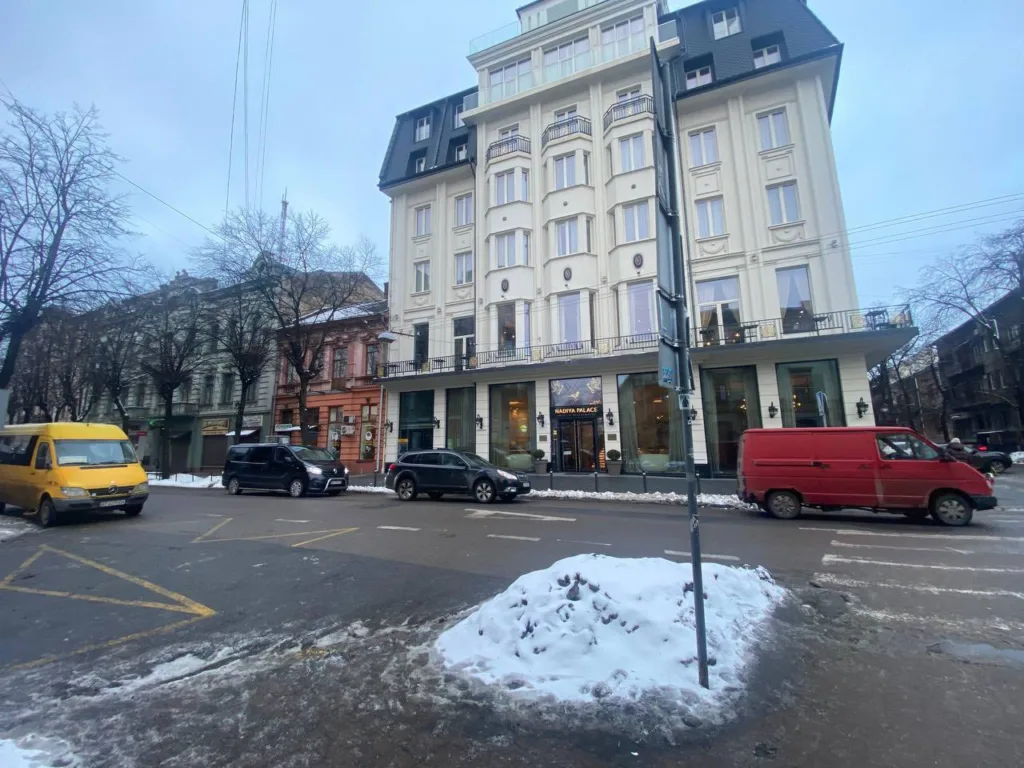 Вулиця з будівлею готелю та припаркованими авто