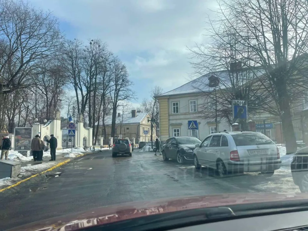 Зимова вулиця з машинами та пішоходами біля будівель