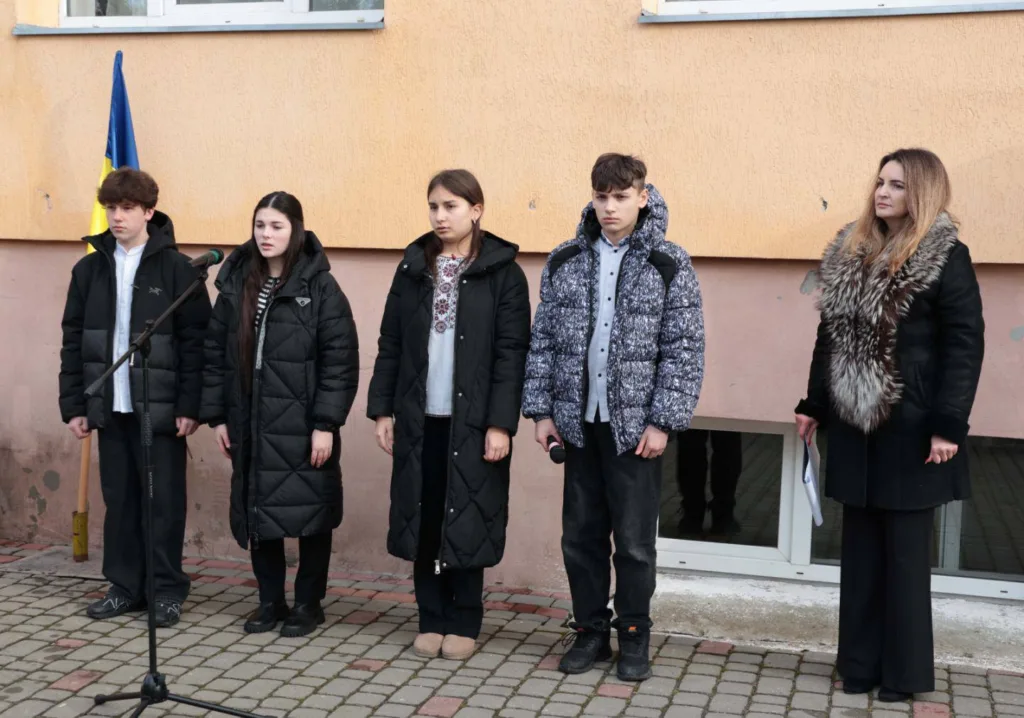 Учні виступають біля школи з українським прапором