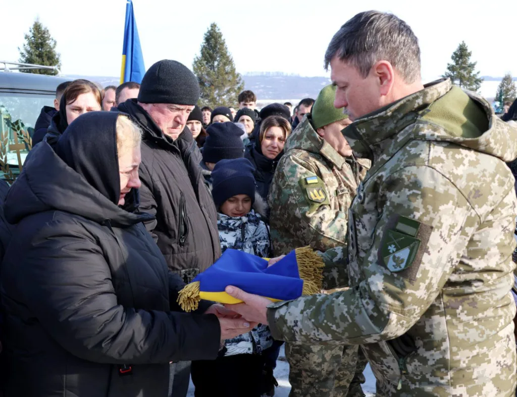 Військовий передає прапор матері загиблого героя