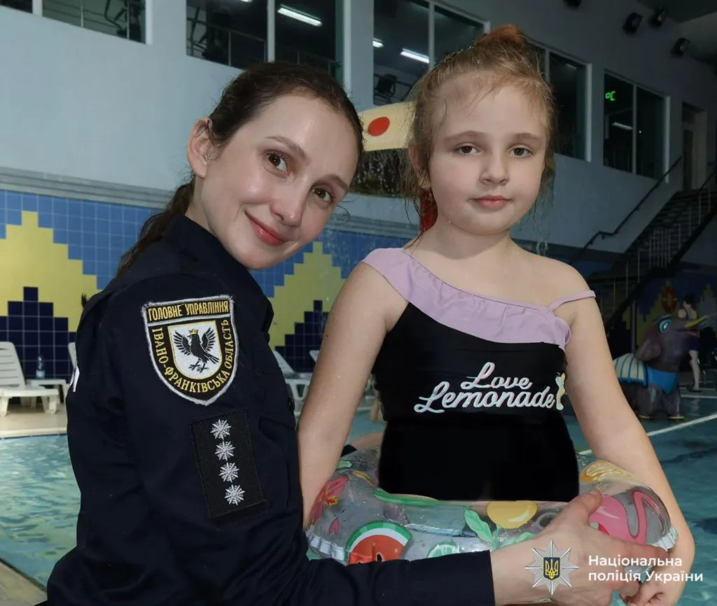 Поліцейська допомагає дитині в басейні