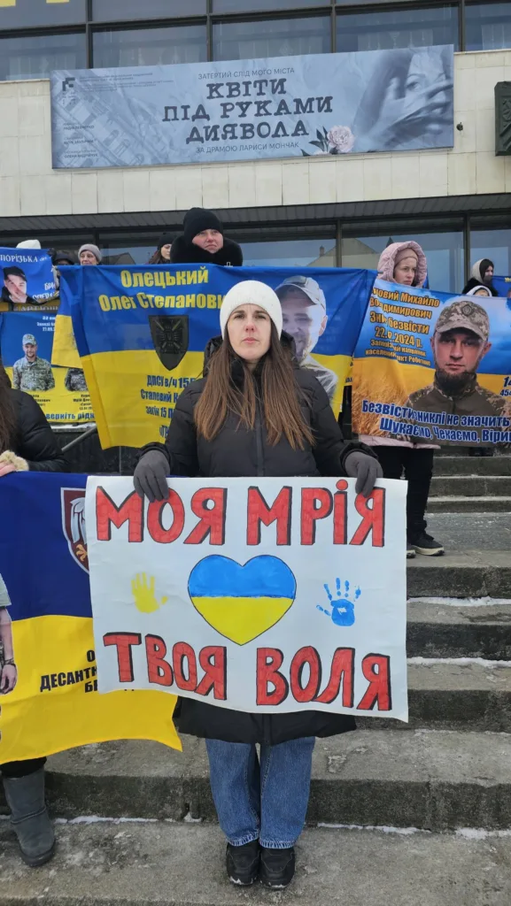 Жінка тримає плакат з українським прапором