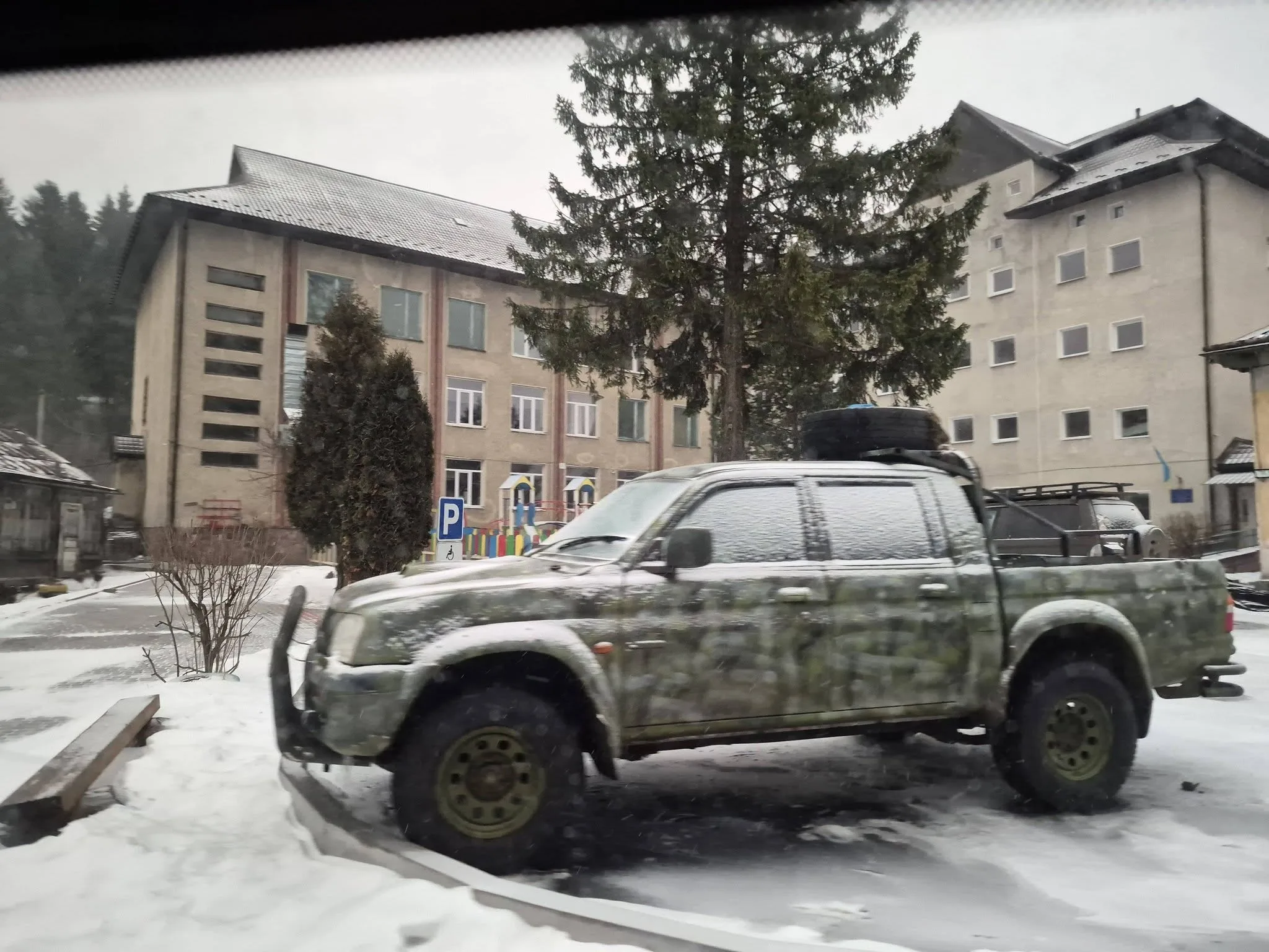 Камуфльований пікап припаркований біля будівлі взимку