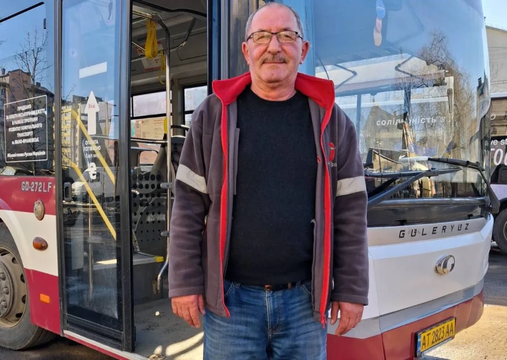 Водій стоїть біля міського автобуса