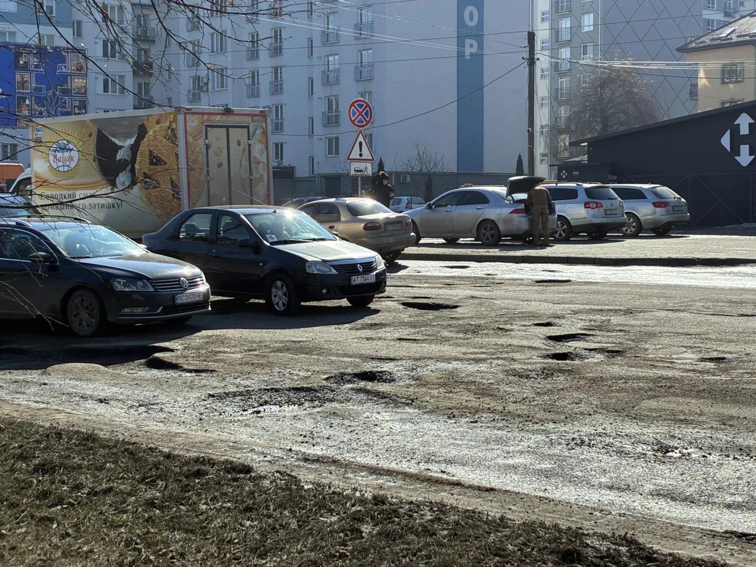 Автомобілі припарковані біля дороги з ямами