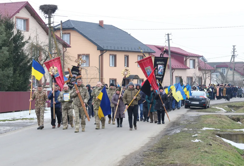 Похоронна хода з українськими прапорами у селі