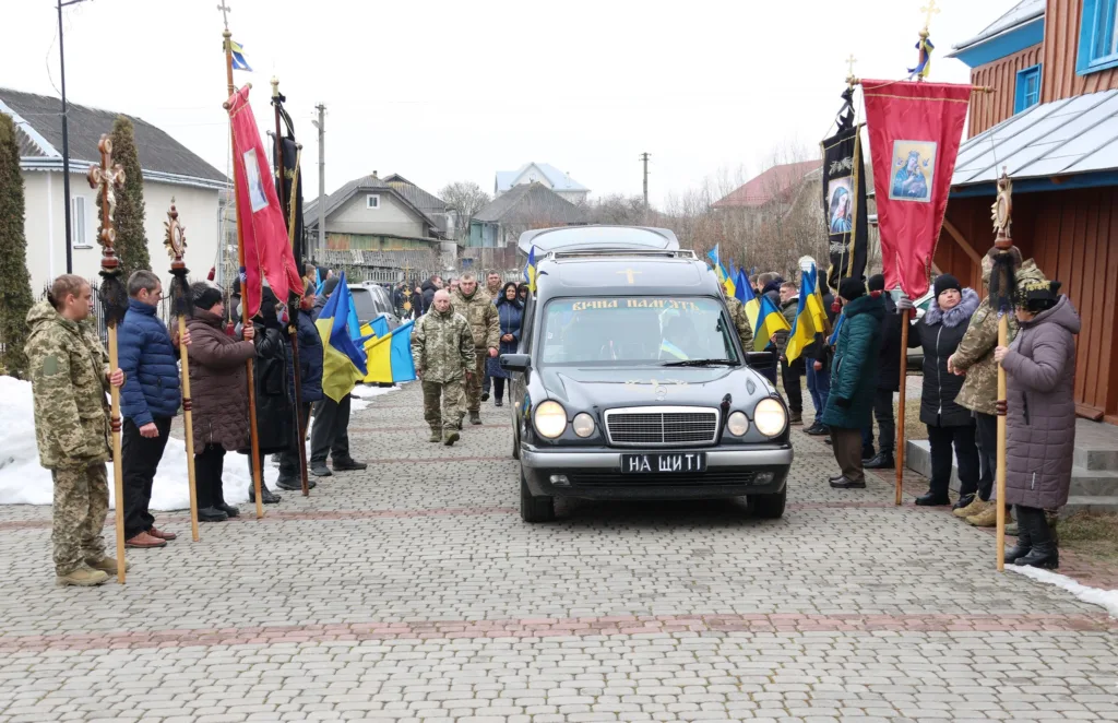 Похоронна процесія з українськими прапорами та військовими