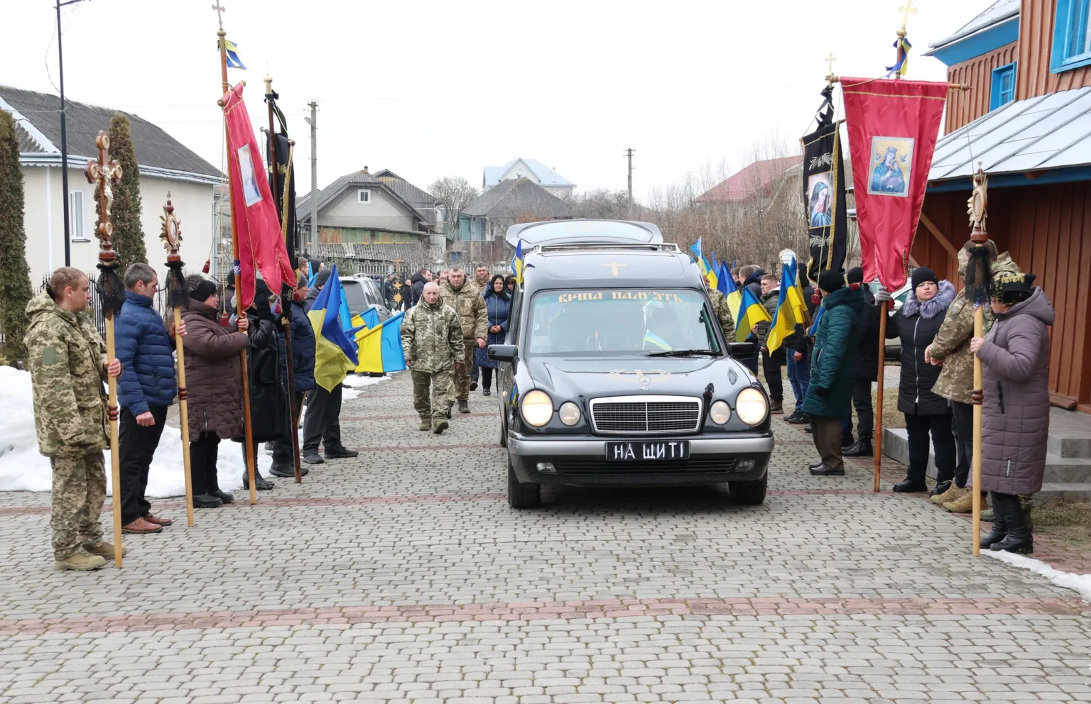 Похоронна процесія з українськими прапорами та військовими