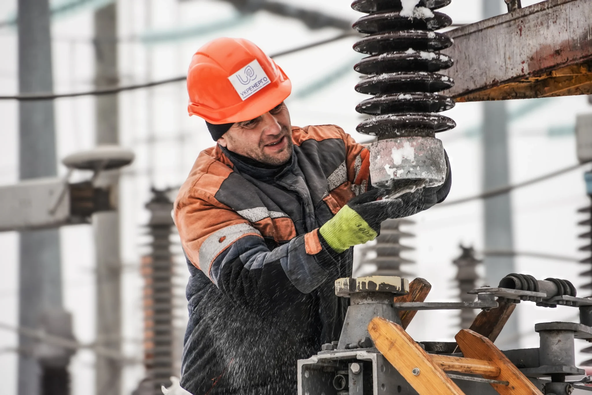 Енергетик ремонтує електрообладнання на підстанції взимку