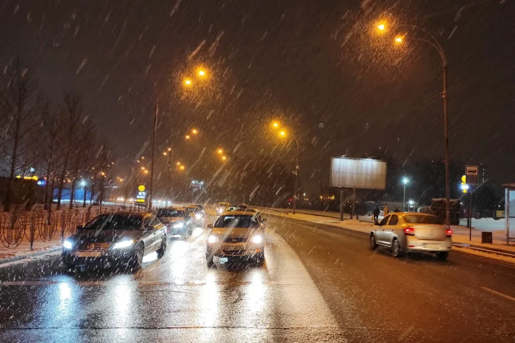Нічне місто, автомобілі на дорозі під снігом