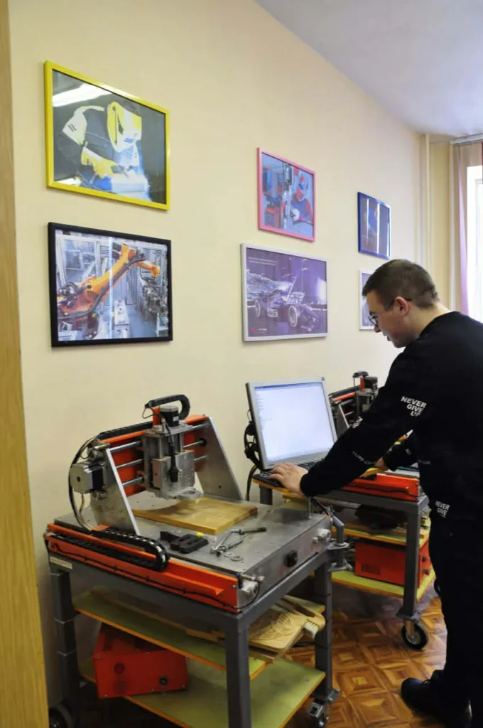 Інженер працює з фрезерним верстатом і комп’ютером