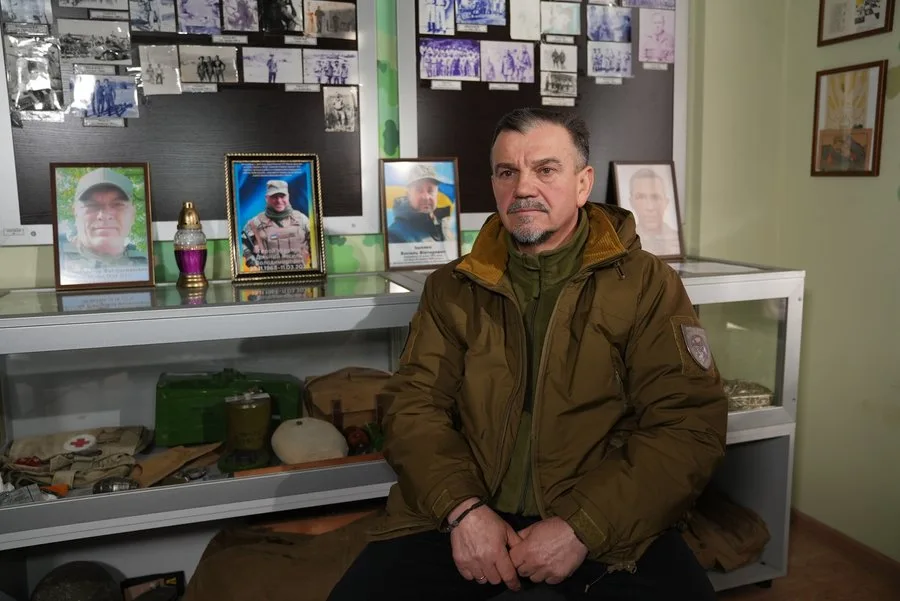 Чоловік у військовій куртці сидить у музеї пам'яті