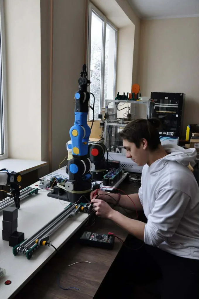 Студент працює з роботизованою рукою в лабораторії