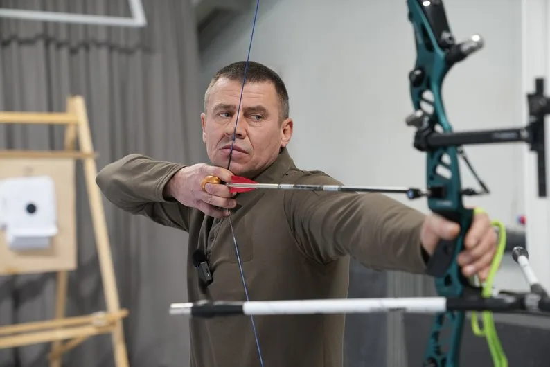 Чоловік натягує тятиву спортивного лука