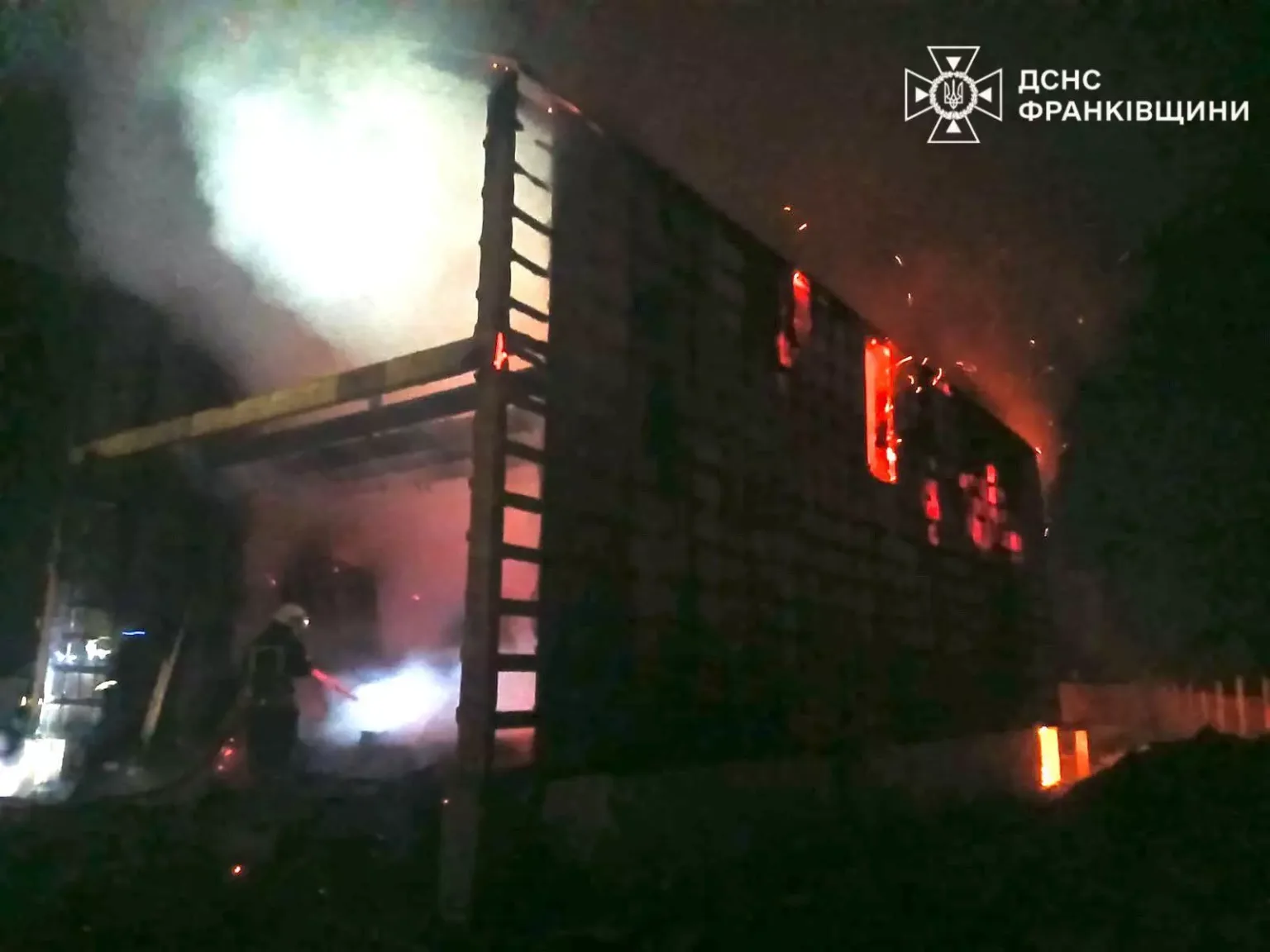 Пожежники гасять вогонь у будівлі вночі