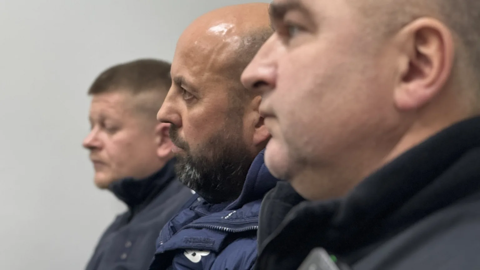 Троє чоловіків у профіль у темному одязі