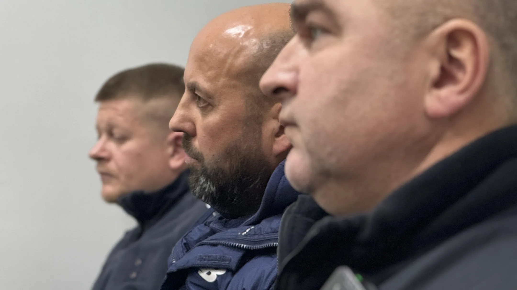 Троє чоловіків у профіль у темному одязі