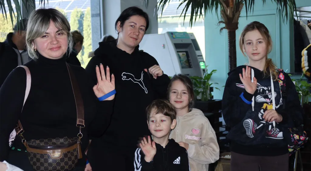 Група людей усміхається та махає рукою