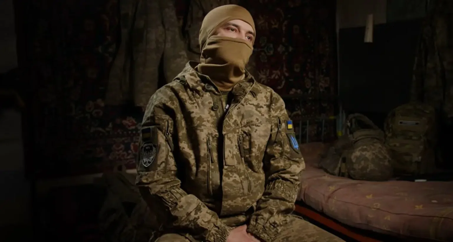 Український військовий у камуфляжі сидить у кімнаті
