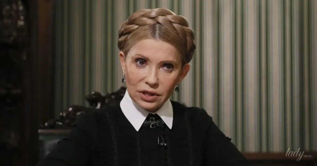 Жінка з косою сидить у кімнаті з шпалерами